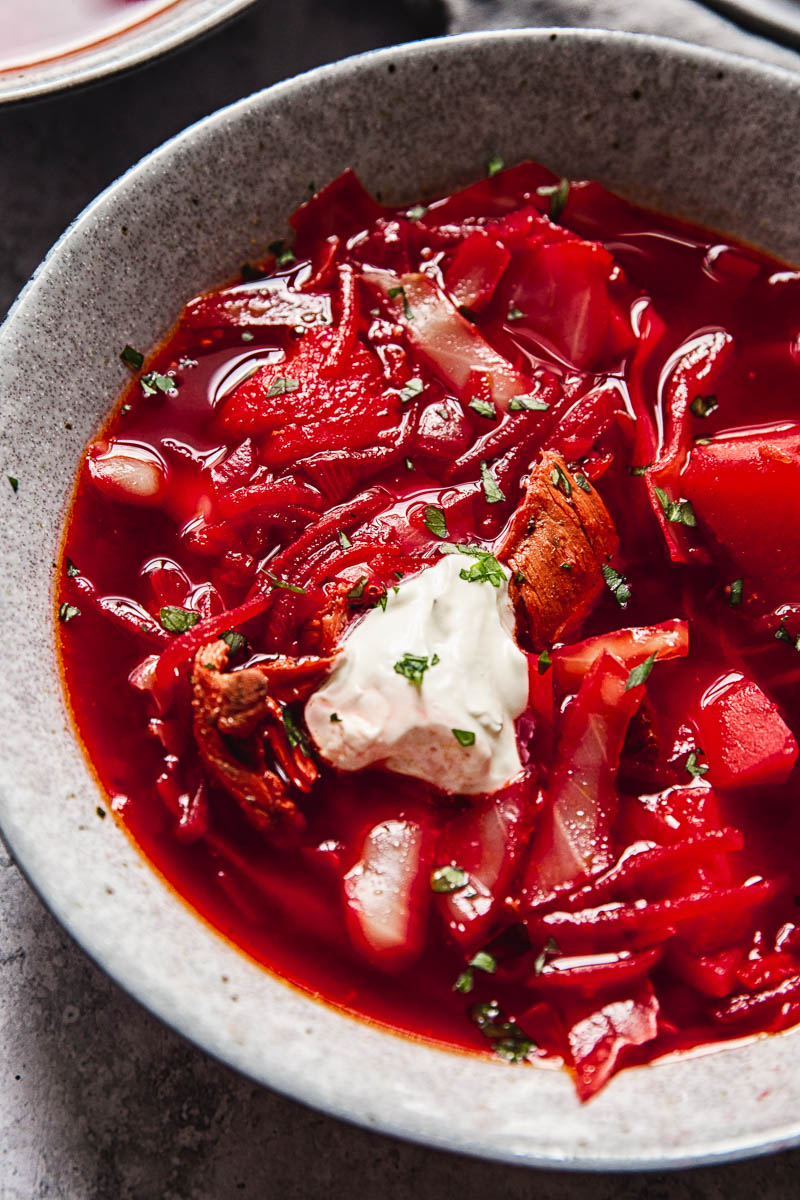 close up of a bowl of borscht with a dollop of sour cream