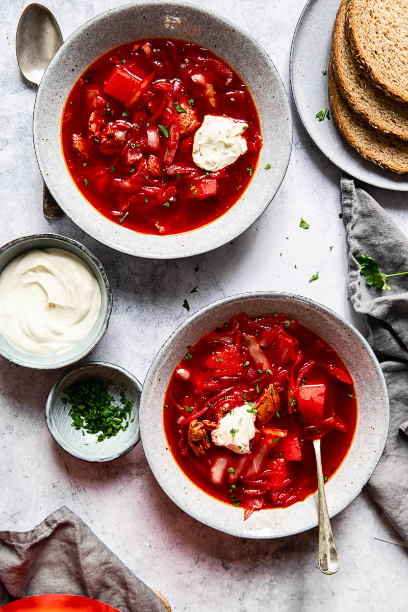 top down of two bowls of borscht with sour cream and parsley