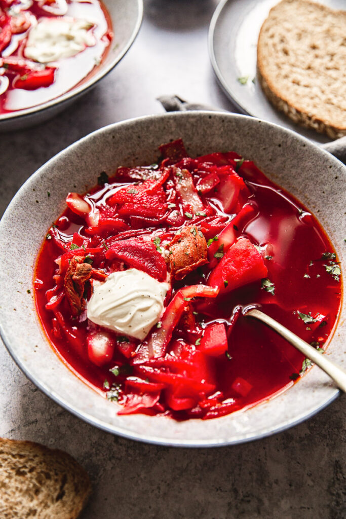 Borscht in a bowl with a spoon and dollop of sour cream