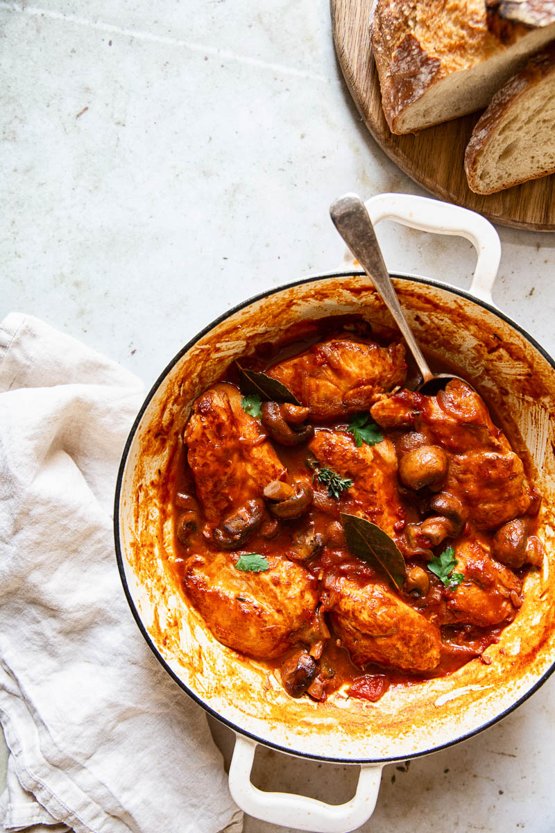 Top down view of Chicken Chasseur in a pan alongside crusty bread