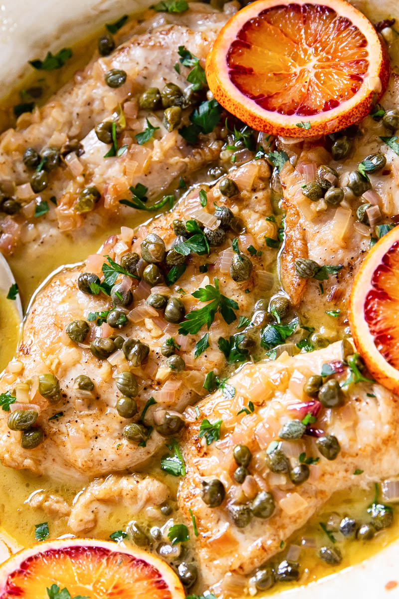 Chicken Paillard topped with parsley, capers and blood orange slices. 