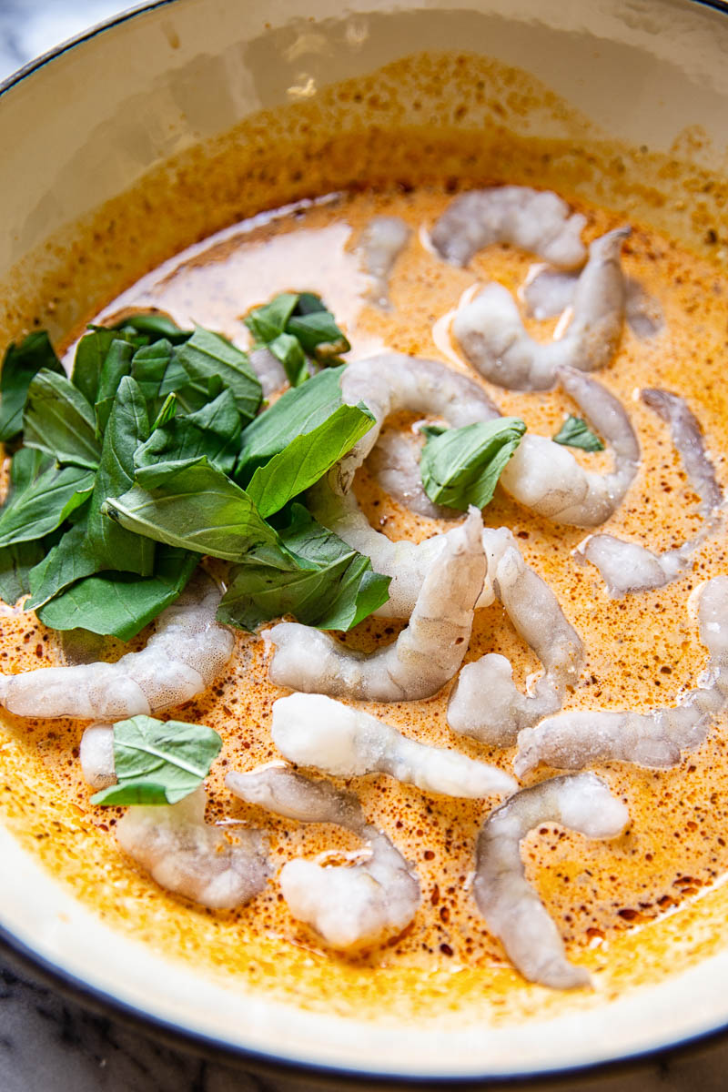 Prawns in creamy sun-dried tomato sauce with fresh basil in white pan