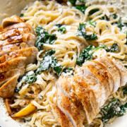 Spinach ricotta linguine with sliced lemon butter chicken in white pan