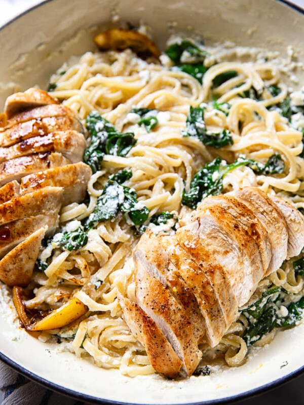 Spinach ricotta linguine with sliced lemon butter chicken in white pan