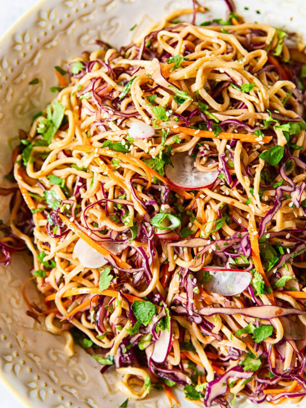 Asian noodle salad with red cabbage, carrots and radishes, sprinkled with green onions and sesame seeds.