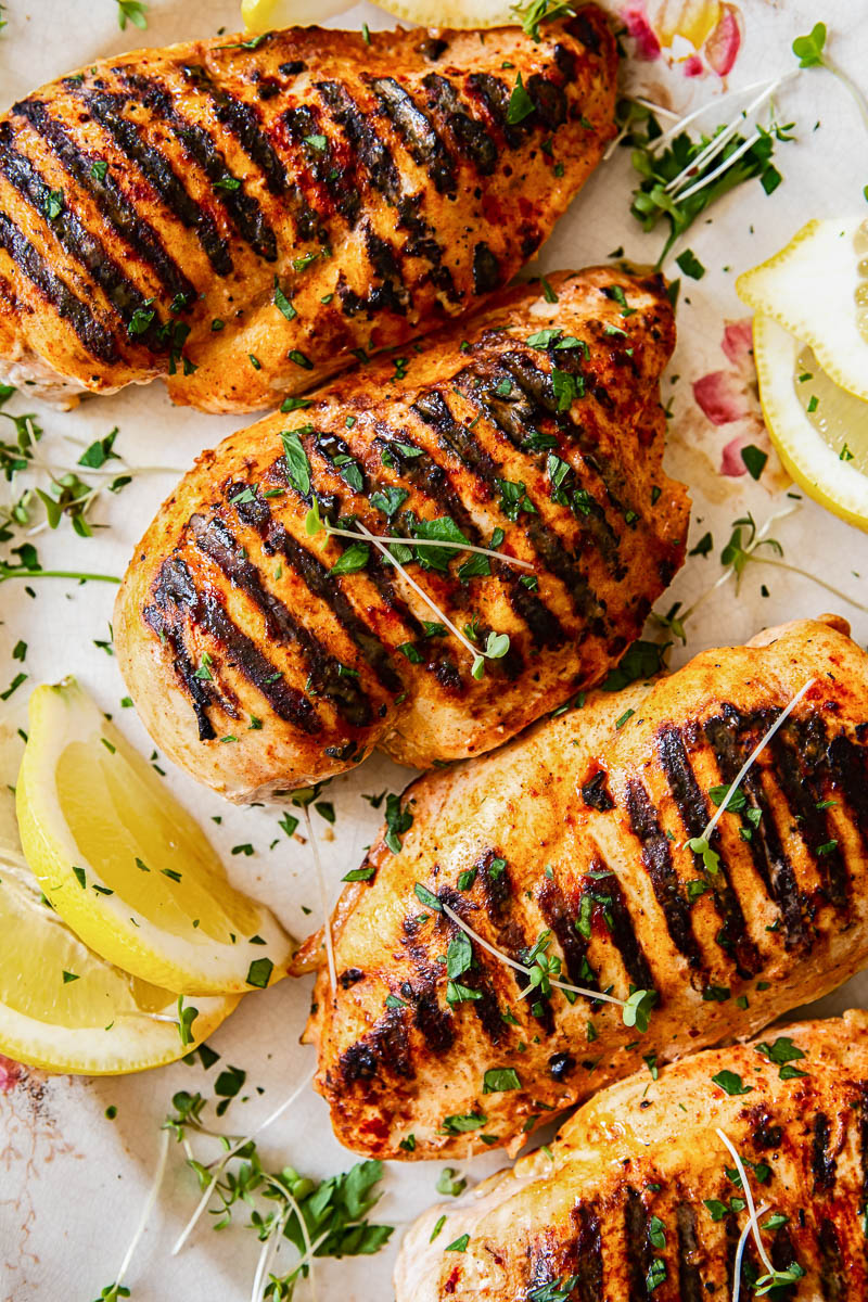 grilled chicken breasts sprinkled with micro herbs and garnished with lemon slices