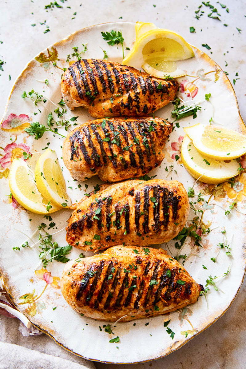 grilled chicken breasts with slices of lemon on platter