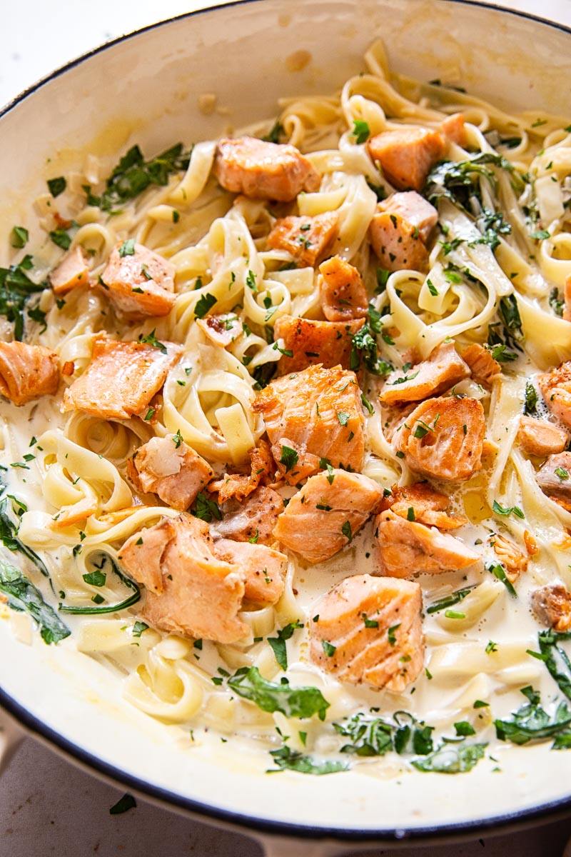 Salmon Pasta with greens in a white pan.