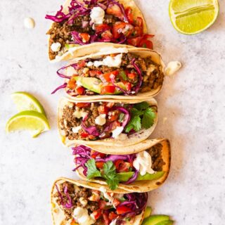 Ground Beef Tacos topped with salsa, avocado slices and red cabbage slaw.