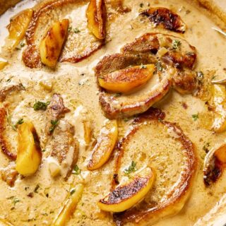 Pork chops and apples in creamy apple cider sauce in a cast iron pan