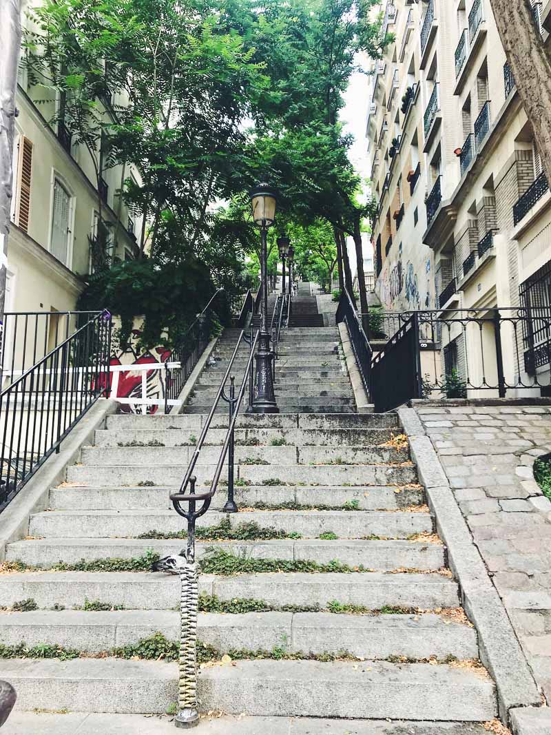 Set of stairs in Montmartre, with buildings at the sides and trees at the top