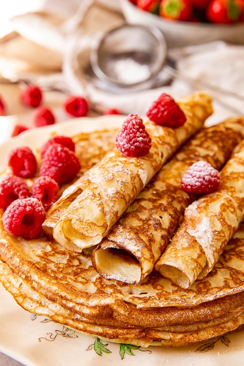 Russian Crepes Blini sprinkled with powdered sugar and topped with raspberries