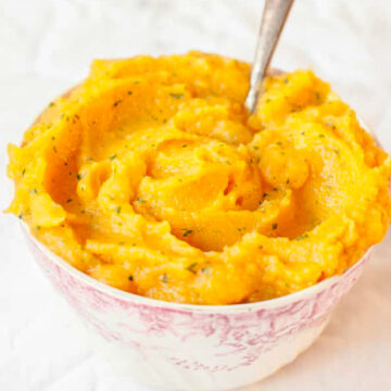 Sweet potato and swede mash in a bowl on while background