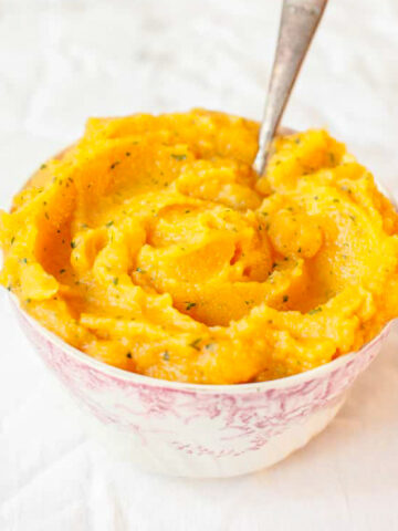 Sweet potato and swede mash in a bowl on while background