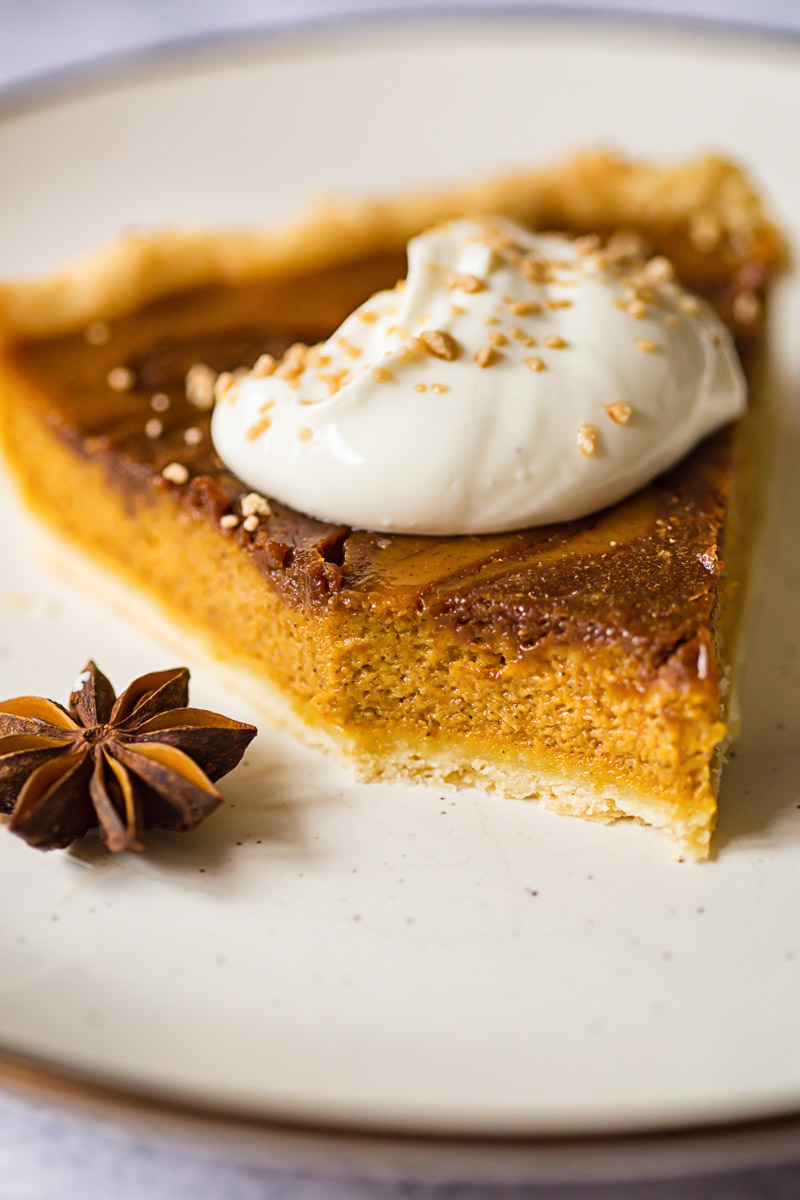 pumpkin pie slice topped with whipped cream and maple sugar