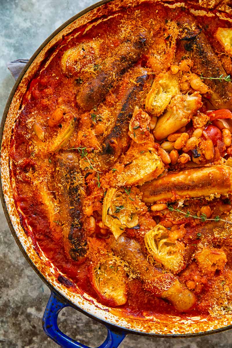 Sausages cooked in smoky tomato sauce with white beans and artichokes. 