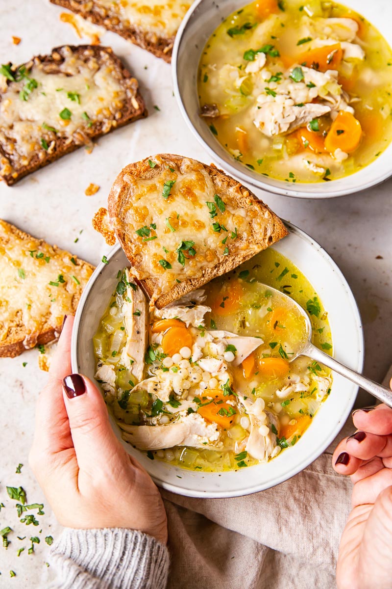Turkey and giant couscous soup in grey bowl with cheese toast.