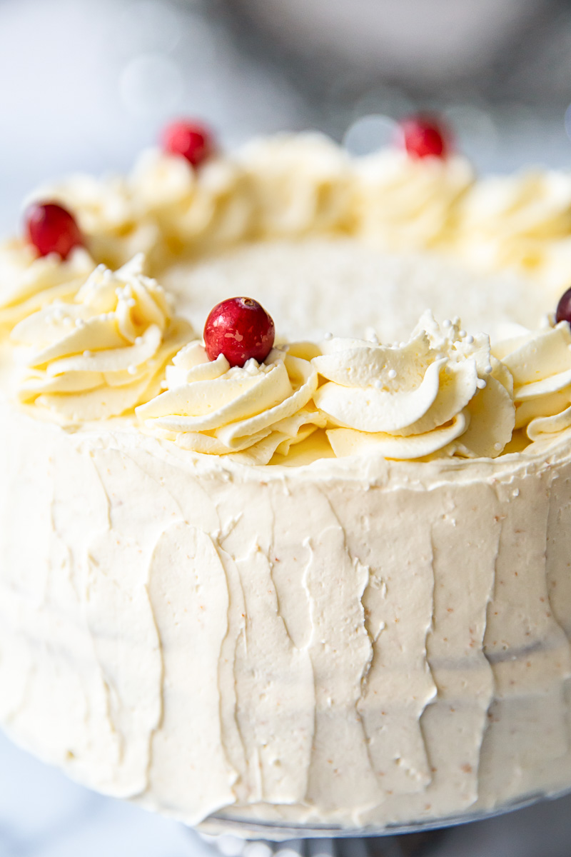Cranberry Cake with Cream Cheese Frosting, decorated with piped rosettes and fresh cranberries 