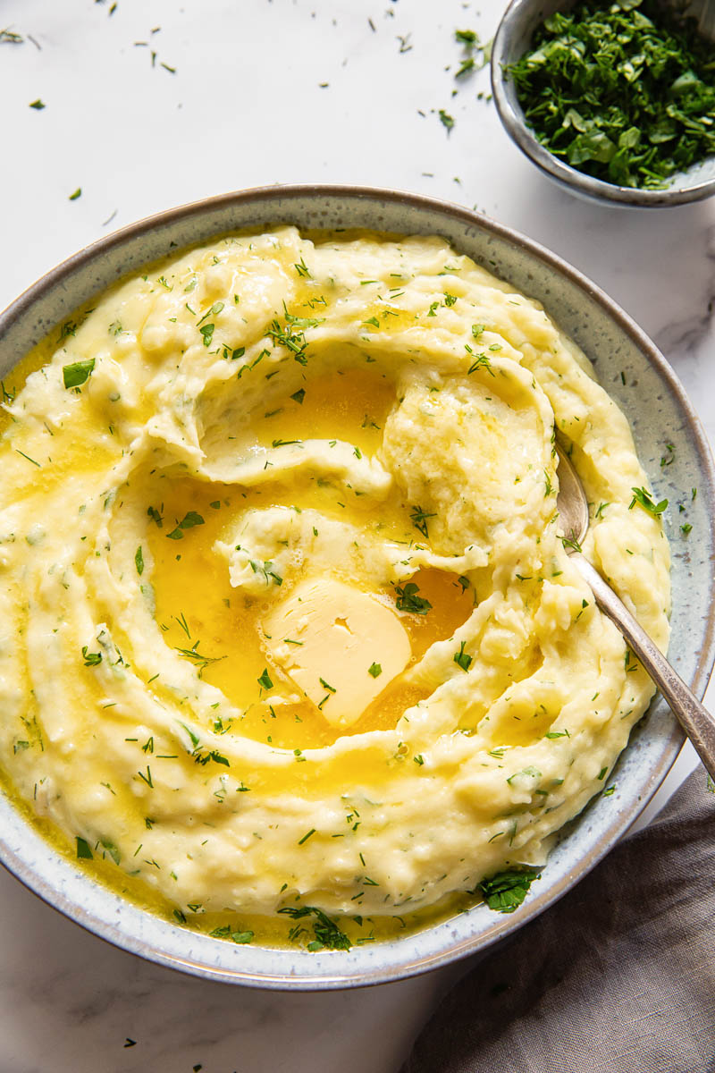 Herby mashed potatoes with melted butter in the center