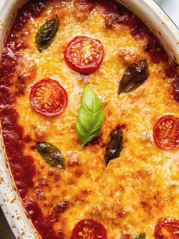 Baked gnocchi topped with melted mozzarella, basil leaves and tomato slices