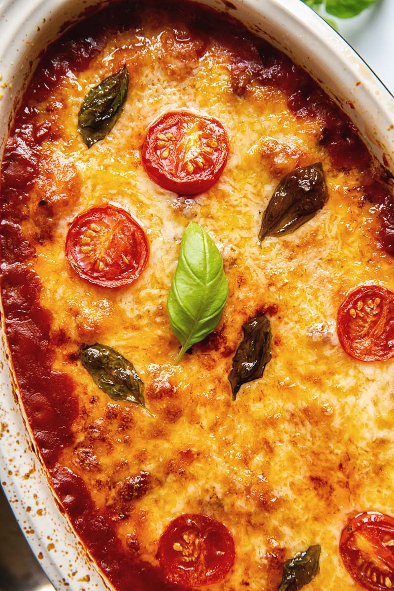 Baked gnocchi topped with melted mozzarella, basil leaves and tomato slices