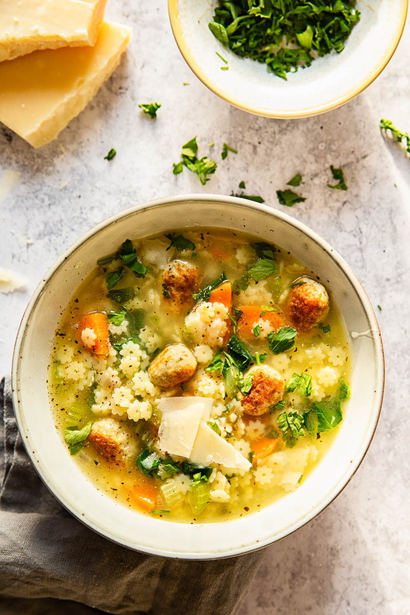 Italian Wedding Soup with chopped parsley and shved Parmesan