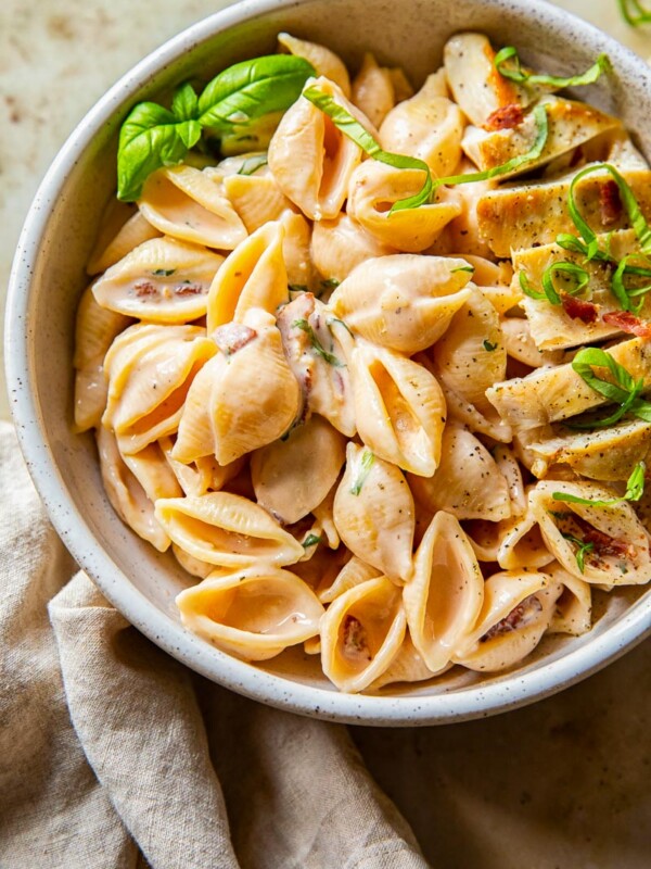 creamy bacon pasta topped with chicken breast and basil