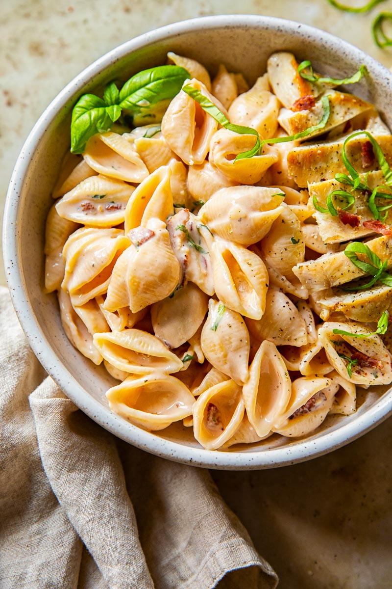creamy bacon pasta topped with chicken breast and basil 