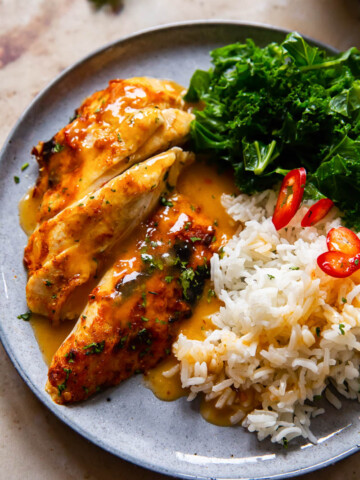glazed chicken breast, rice and kale on a grey plate