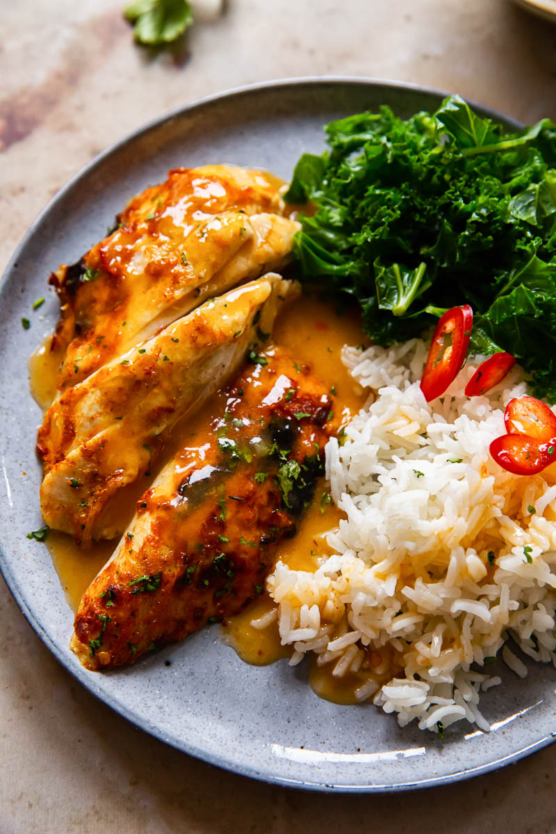 glazed chicken breast, rice and kale on a grey plate