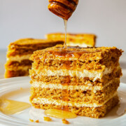 Russian honey cake slice with honey drizzled from above.