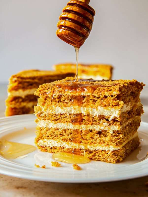 Russian honey cake slice with honey drizzled from above.