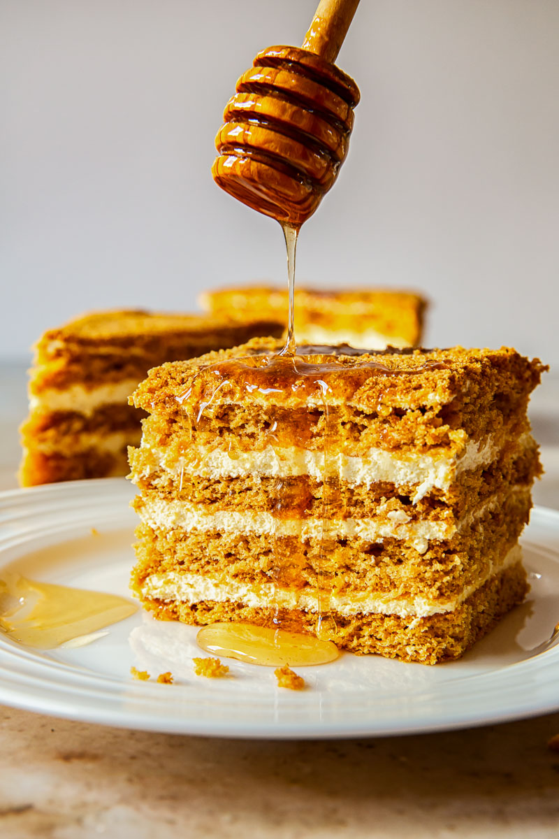 Russian honey cake slice with honey drizzled from above. 