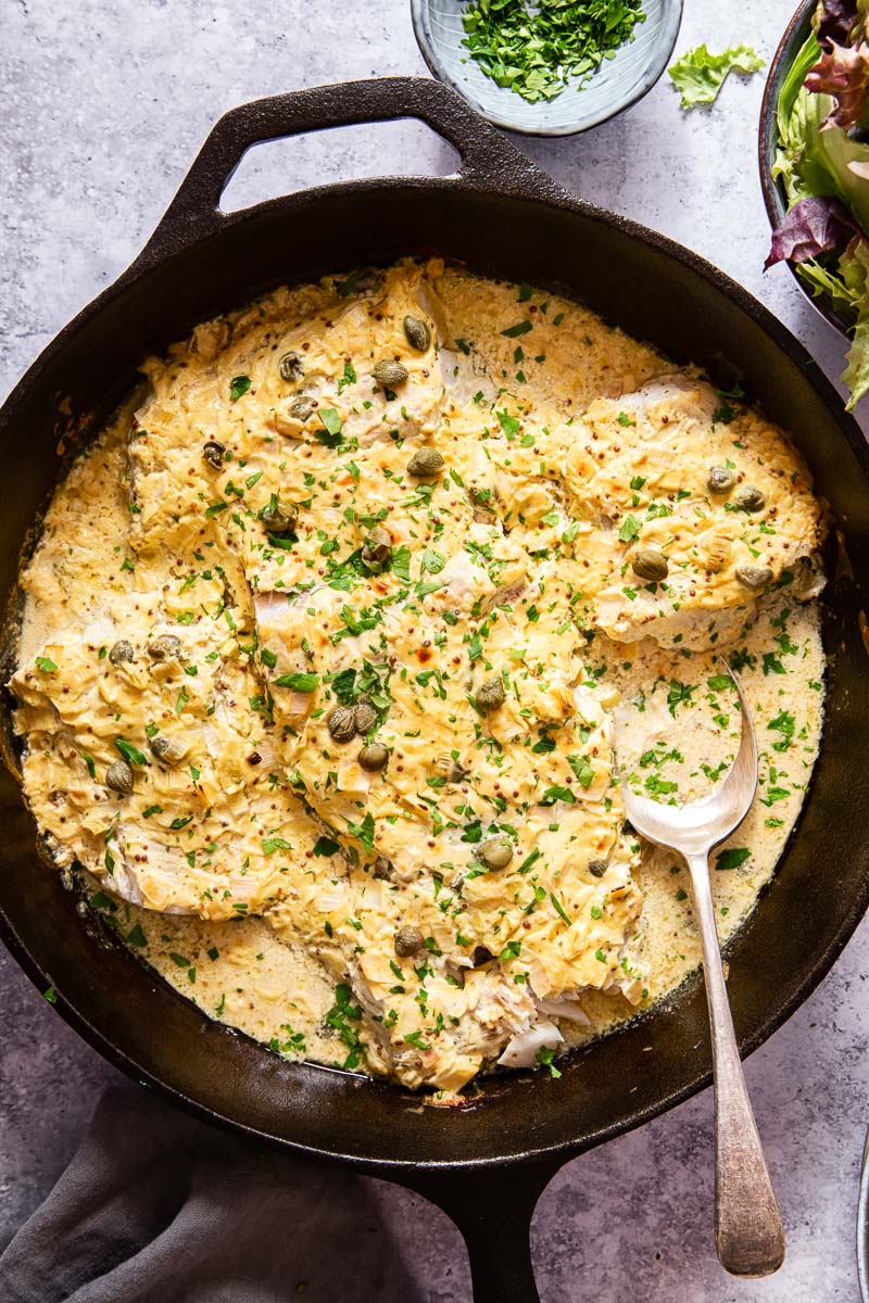 baked fish in cream sauce in black skillet