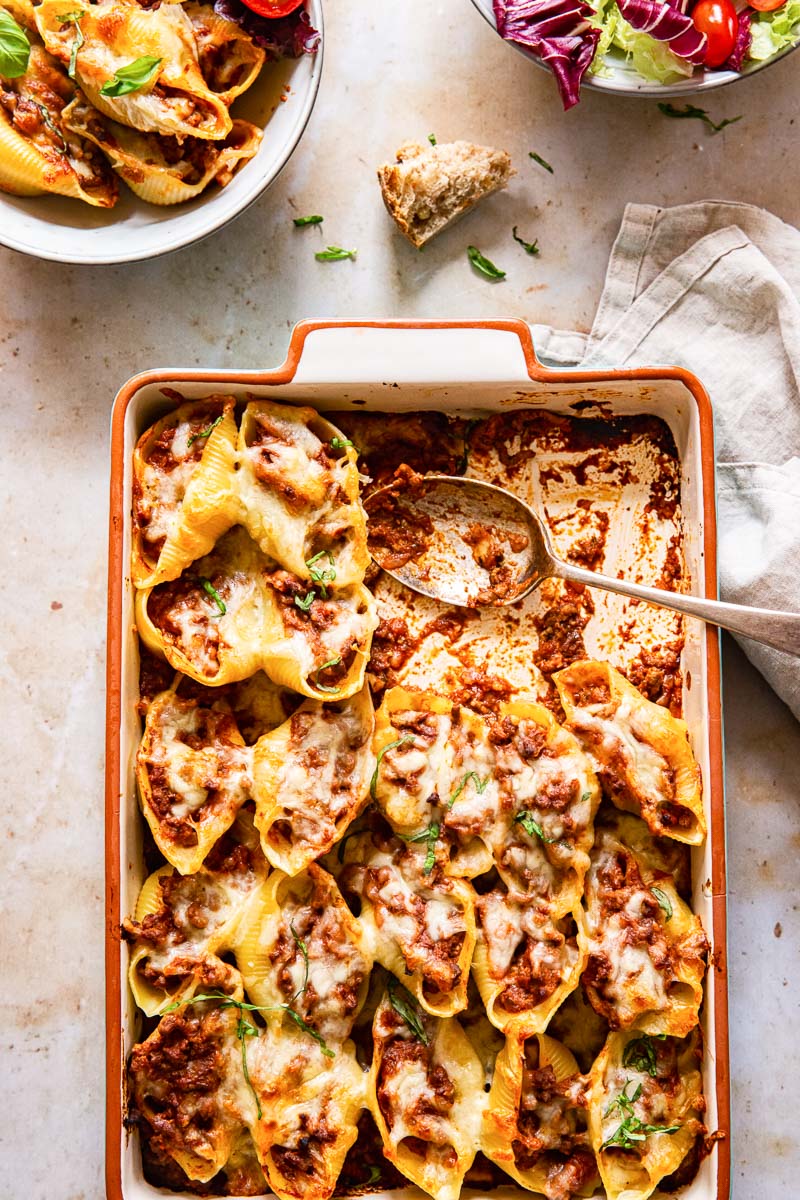 rectangular pan with baked pasta, salad bowl and pasta bowl