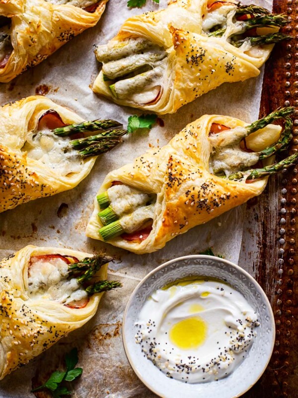 cheese and asparagus puff pastry pockets on baking sheet a small dish with dip