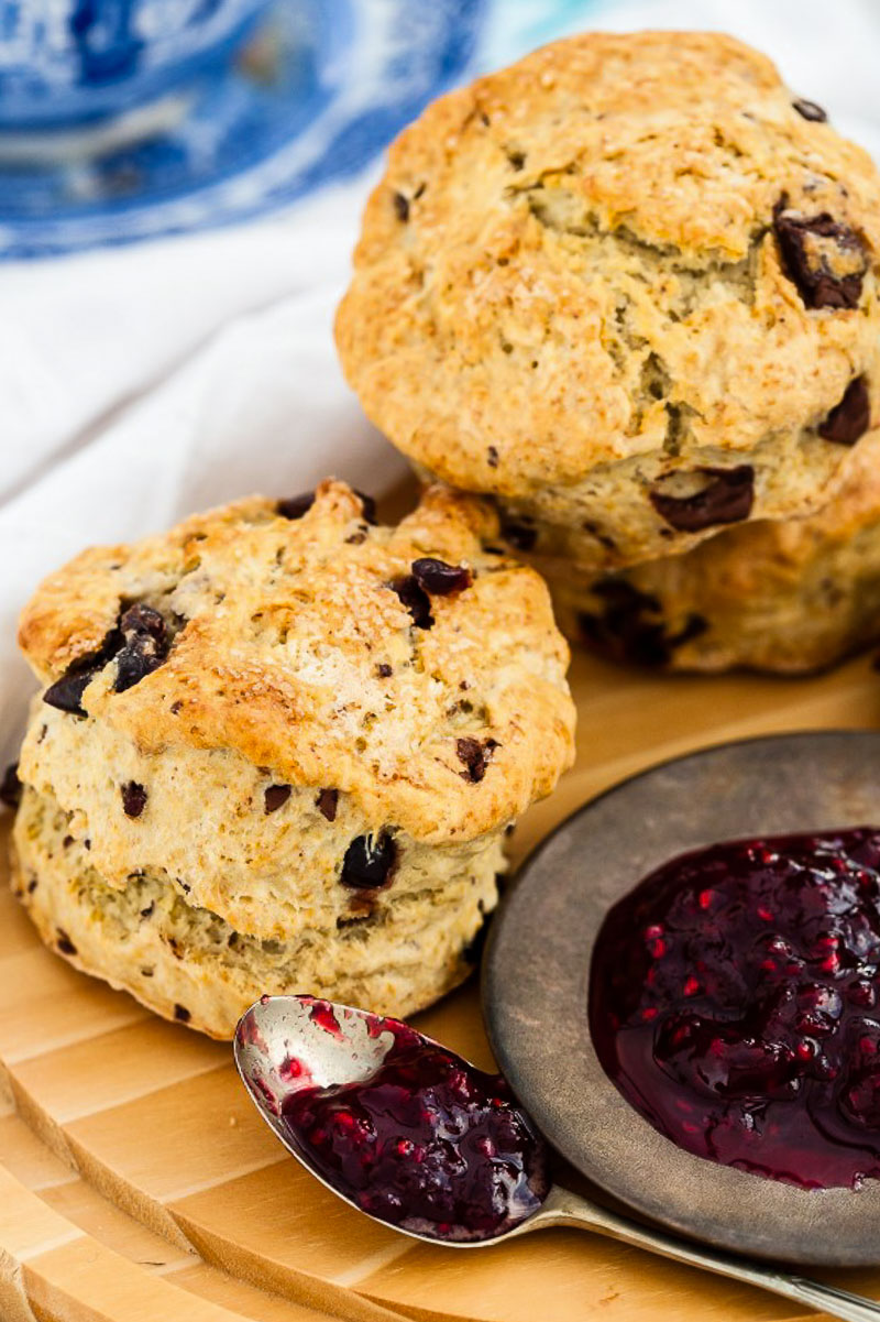 two scones and raspberry jam on wooden board