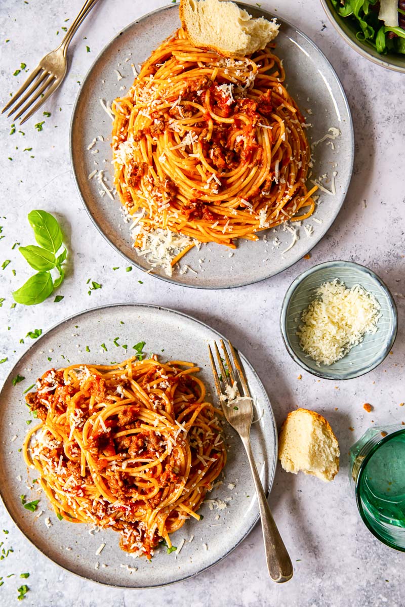 overhead image of two grey plate with spaghetti with red meat sauce