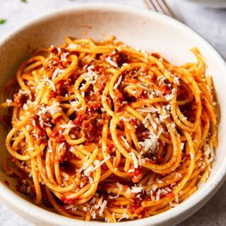 spaghetti bolognese sprinkled with Parmesan in cream bowl