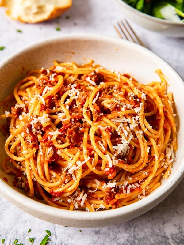 spaghetti bolognese sprinkled with Parmesan in cream bowl