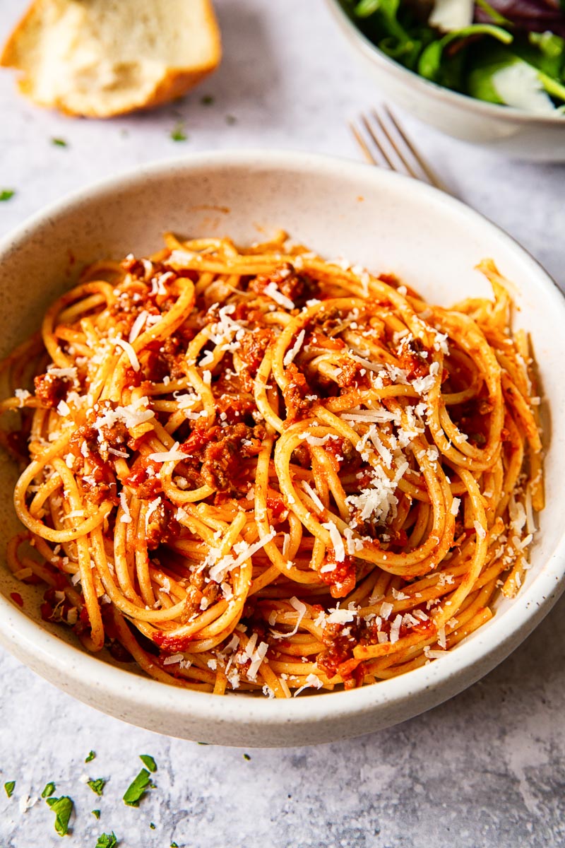spaghetti bolognese sprinkled with Parmesan in cream bowl