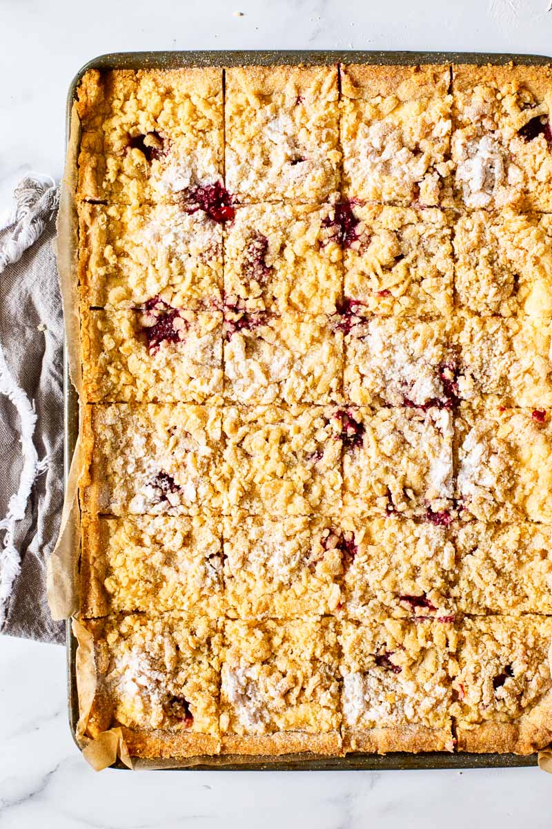 a sheet pan with cheesecake bars on white background