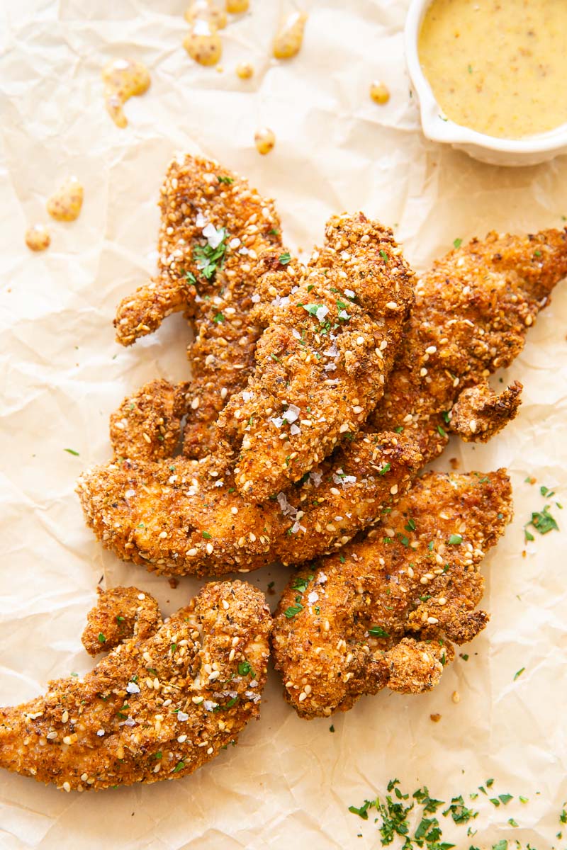 crispy chicken tender on brown wax paper and honey mustard sauce in small white dish