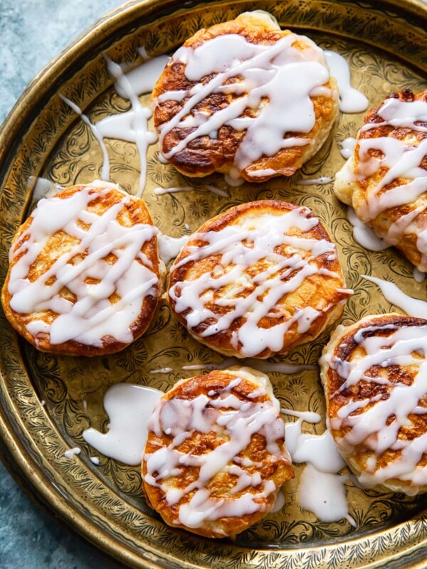 overhead view of apple fritters drizzled with sugar glaze on platter