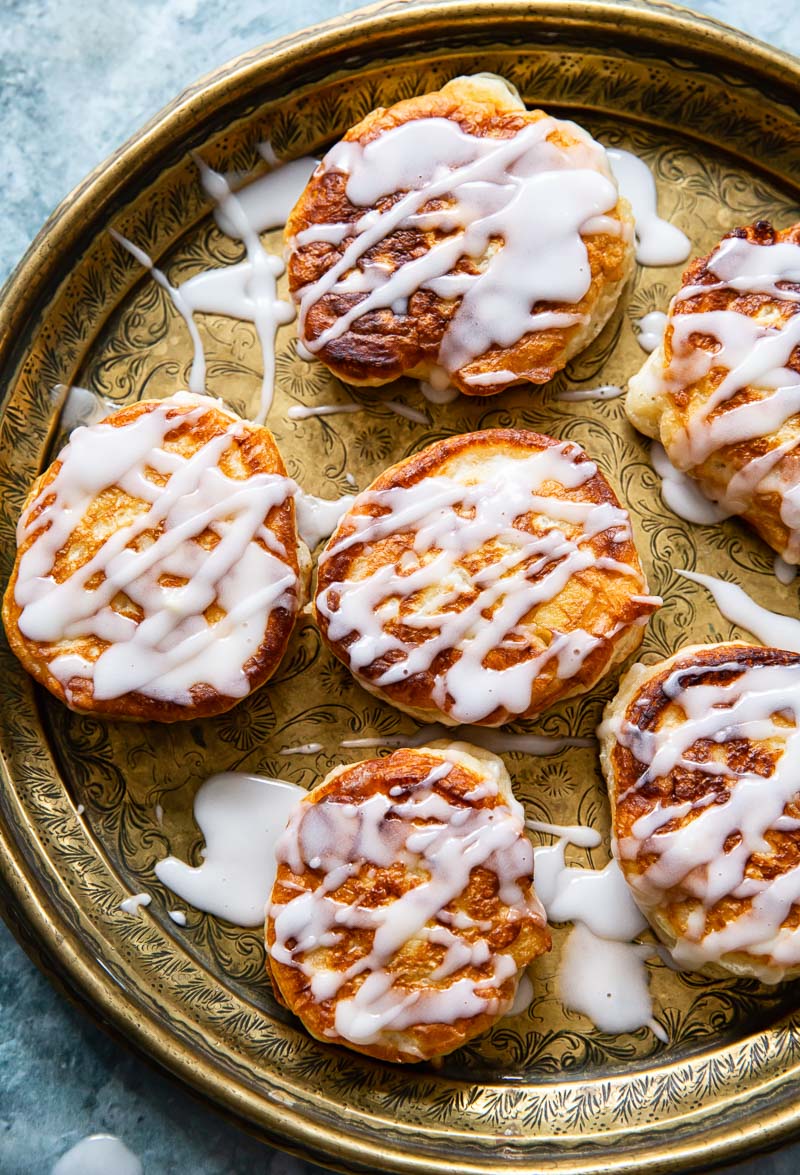 overhead view of apple fritters drizzled with sugar glaze on platter