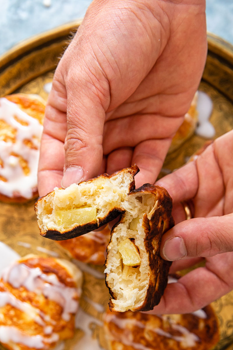 apple fritter broken in half with apples chunks showing.