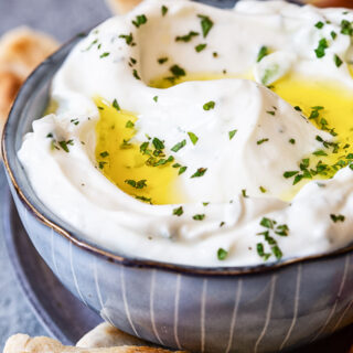 Tzatziki sauce in blue bowl, pita bread around it.