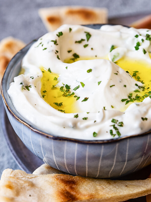 Tzatziki sauce in blue bowl, pita bread around it.