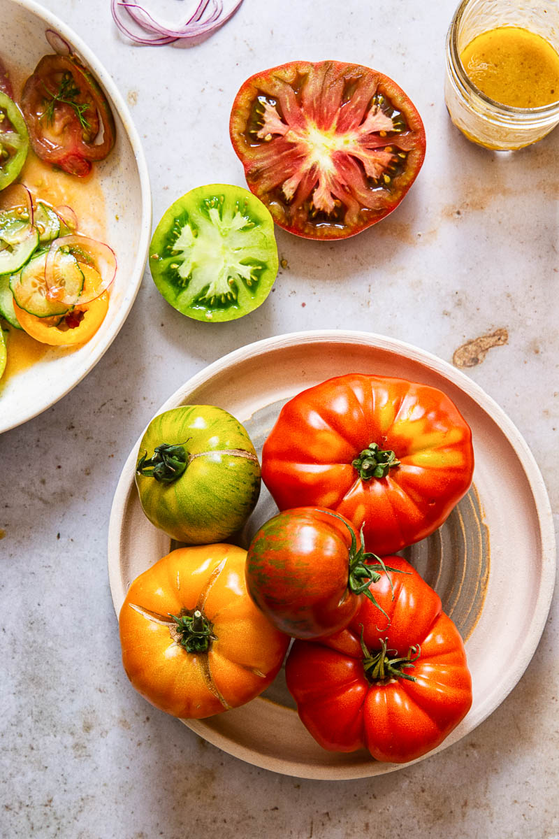 heirloom tomatoes on a plate, cut red and green tomatoes and salad dressing