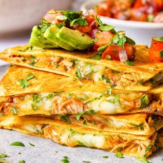 quesadilla pieces stacked on top of each other and topped with avocado and pico de gallo